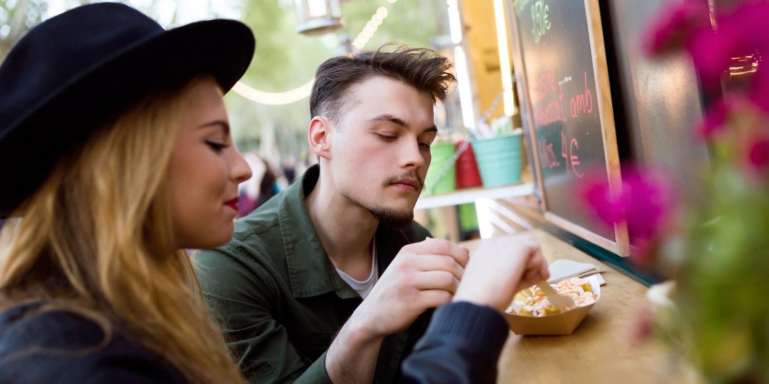 Portrait of beautiful young couple visiting eat market in the street.