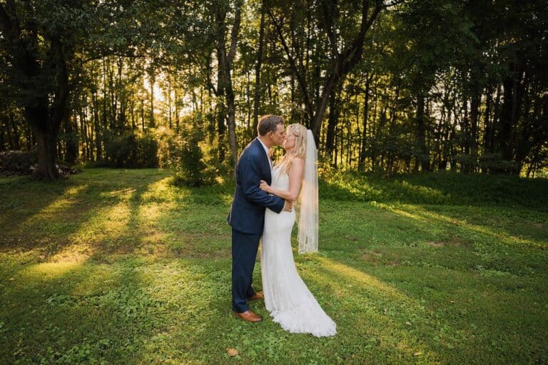 Couple Kissing Outside with Green Grass and Trees in Background